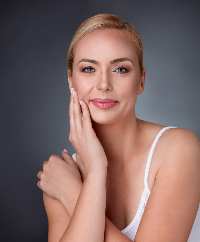Woman smiling looking to the camera touching her cheek