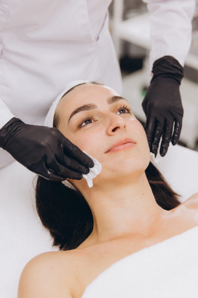 Beautician Cleaning Face of Woman in Beauty Salon