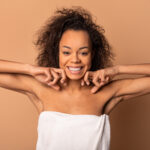 Smiling woman with natural curly hair showing underarms after hair removal